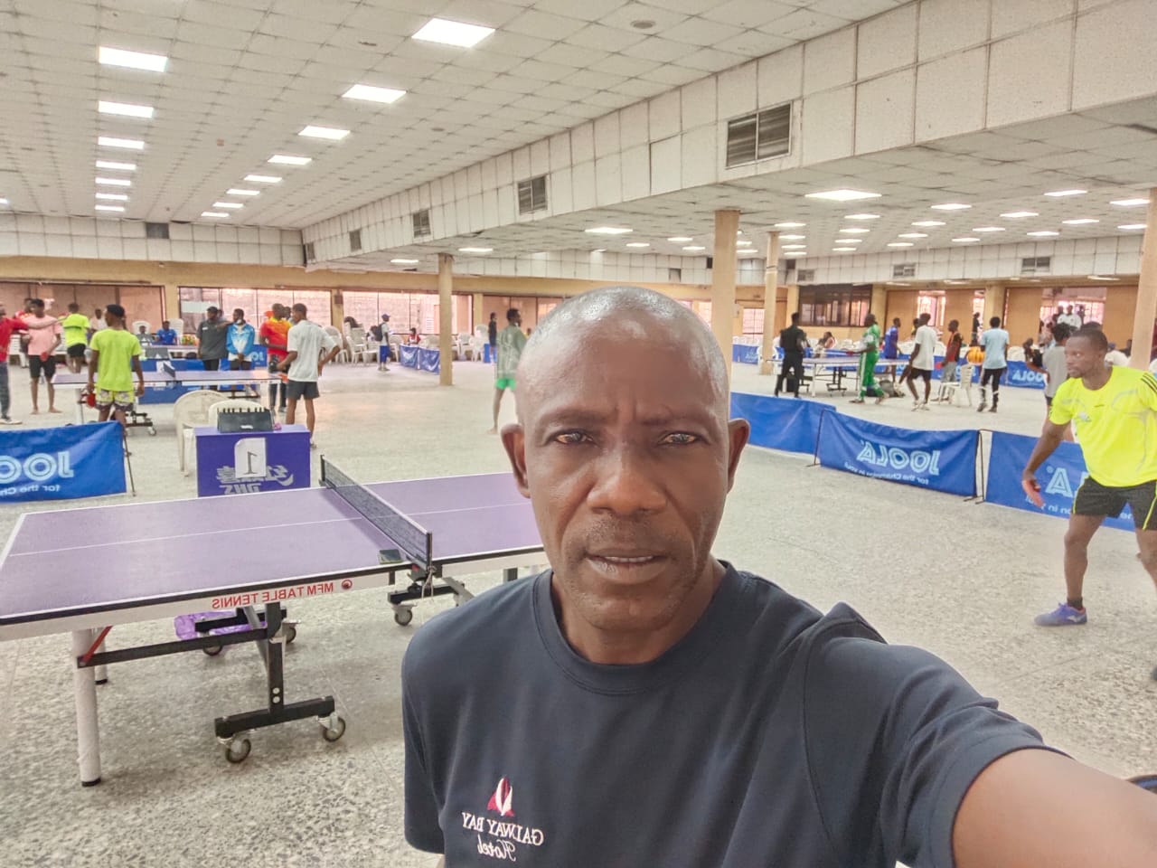 Coach Laja at a packed table tennis tournament hall in Lagos